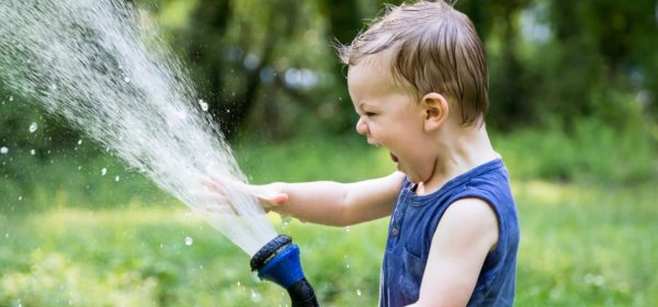 Un enfant jouant avec un tuyau d'arrosage