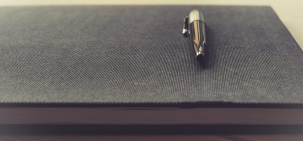 un stylo posé sur un cahier de note.